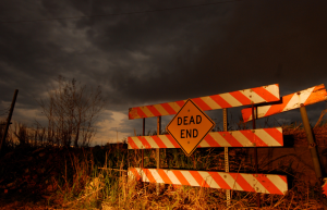 Dead End road sign barrier against a background of a dark and ominous sky